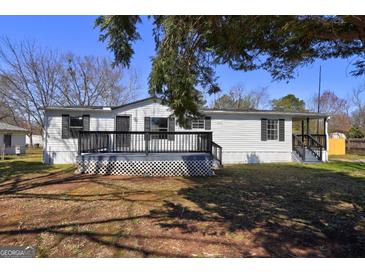 Charming single-story home featuring a covered porch and freshly painted white siding and black shutters at 152 Skyland E Dr, Locust Grove, GA 30248