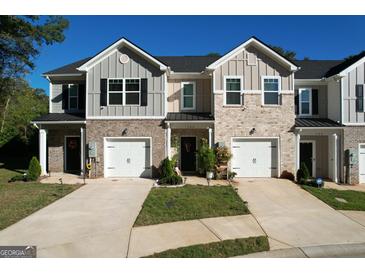 Charming townhouse featuring a brick facade, attached garage, and well-manicured front lawn at 142 Hampton Cir, Mcdonough, GA 30253