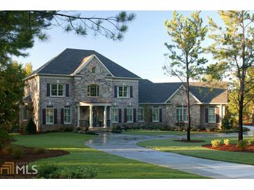Stunning stone home with a circular drive and lush front lawn and manicured landscaping at 315 Westbourne Dr, Tyrone, GA 30290