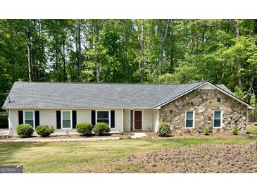 Charming single-story home featuring stone accents, black shutters, and a lush green lawn at 122 Hilo Rd, Fayetteville, GA 30215