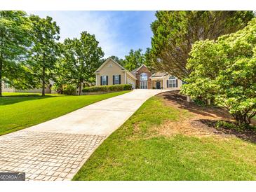 Charming home featuring a well-manicured lawn, beautiful landscaping and a long concrete driveway leading to a two-car garage at 120 Lyndhurst Way, Sharpsburg, GA 30277