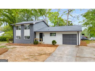 Charming two-story home featuring a gray-and-white painted brick, updated windows, and a well-manicured front yard at 410 Queen Aliese Ln, Jonesboro, GA 30236