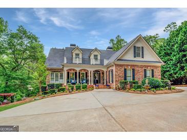 Stately brick home with a circular driveway, manicured landscaping, and charming balcony details at 95 Weslyan Way, Oxford, GA 30054