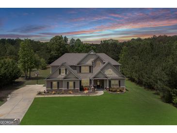 Beautiful two-story home with lush lawn and mature trees against a dramatic twilight sky at 127 Grayson Myers Dr, Villa Rica, GA 30180