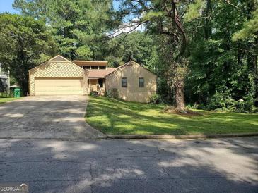 Charming single-Gathering home with attached garage and inviting curb appeal surrounded by lush greenery and mature trees at 3244 Harbor Woods Rd, Decatur, GA 30034