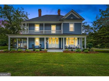Charming two-story blue home featuring a large wrap-around porch and well-manicured lawn at 29 Indian Creek Rd, Locust Grove, GA 30248