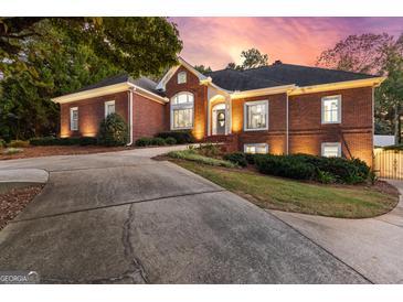 Elegant brick home with manicured landscaping, driveway, and warm exterior lighting at sunset at 248 Montrose Dr, Mcdonough, GA 30253