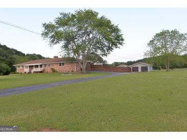 Charming ranch-style home featuring a well-maintained lawn, brick exterior, and a long driveway leading to a detached garage at 2647 Mount Carmel Rd, Hampton, GA 30228