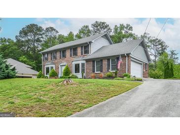 Two-story brick home with an attached garage and meticulously maintained landscaping offers classic charm at 830 Montego Sw Way, Lilburn, GA 30047