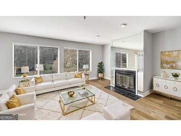 Bright living room boasts hardwood floors, fireplace, and large windows at 27 Lakes Edge Se Dr, Smyrna, GA 30080