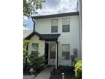 Charming two-story townhouse with white siding, black roof, and well-maintained front yard with security at 2353 Wellington Cir, Lithonia, GA 30058
