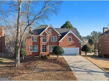 Traditional red brick two-story home with a two-car garage, manicured lawn, and mature trees on a sunny day at 4683 Heritage Lakes Sw Ct, Mableton, GA 30126