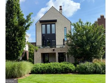 Modern two-story home featuring brick facade, balcony, large windows, and a well-manicured lawn at 145 Kelmscott Ln, Fayetteville, GA 30214
