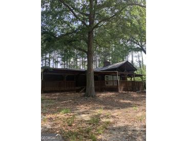 Rustic home featuring a large wrap-around porch, offering an inviting space to relax in a secluded, wooded setting at 3255 Flat Shoals Sw Rd, Conyers, GA 30094