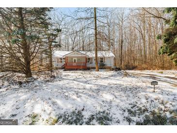Charming single-story home with a cozy front porch and snowy front yard surrounded by trees at 5552 Smithfield Rd, Bowdon, GA 30108