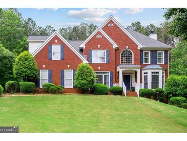 Traditional brick home with a manicured lawn, blue shutters, and beautiful landscaping, perfect for suburban living at 495 Stonehaven Dr, Fayetteville, GA 30215
