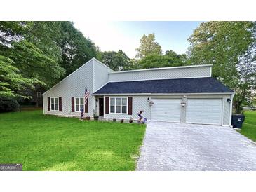 Charming home featuring an attached two-car garage, landscaped yard, and traditional shutters at 104 Hillmont Dr, Woodstock, GA 30188