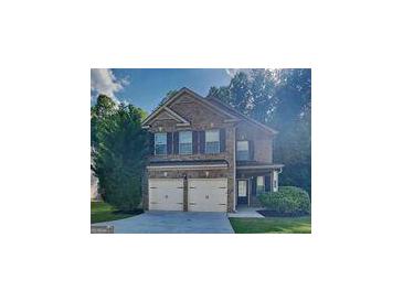Charming two-story brick home with a two-car garage and a well-manicured lawn at 749 Rolling Downs Dr, Loganville, GA 30052