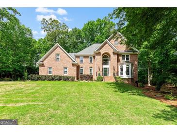 Beautiful brick two-story home with a well-manicured lawn and mature trees at 255 Emerald Lake Dr, Fayetteville, GA 30215
