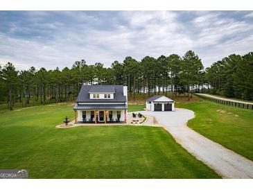 Beautiful farmhouse-style home with lush green lawn and tree-lined backdrop at 211 Hogan Coweta Rd, Hogansville, GA 30230