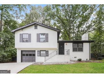Charming two-story home with a well-manicured lawn, painted white brick and siding, and a grey garage door at 1590 Sw Cherry Hill Ln, Conyers, GA 30094