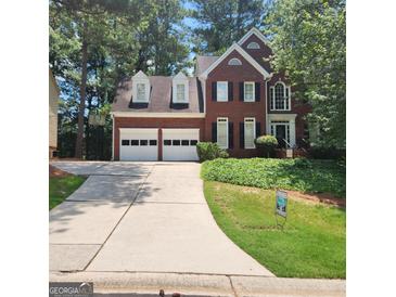 Charming two-story brick home with a two-car garage, dormer windows, and a well-maintained lawn on a sunny day at 171 Galesburg Dr, Lawrenceville, GA 30044