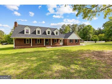 Charming brick home featuring black shutters, dormer windows and a spacious front yard with mature trees at 550 Davis Rd, Fayetteville, GA 30215
