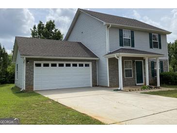Charming two-story home featuring a gray siding, a two-car garage, and a well-maintained front yard at 253 Whistle Way, Locust Grove, GA 30248