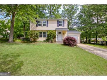 Charming yellow two-story home with a well-manicured lawn, neat landscaping, and attached garage at 131 Sweetgum Rd, Peachtree City, GA 30269