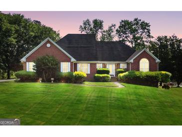Charming red brick home featuring a well-manicured lawn and mature landscaping at 70 Lake Charles Xing, Covington, GA 30016