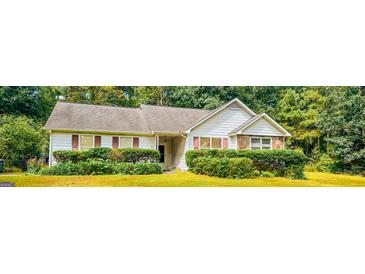 Charming single-story home featuring mature landscaping, white siding, and a stone accent wall at 60 Doe Run Dr, Sharpsburg, GA 30277