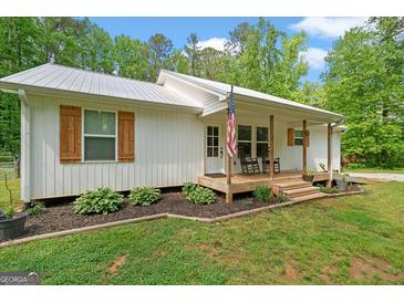 Charming white home with a cozy front porch, rocking chairs, and beautiful landscaping at 180 E Ranchette Rd, Temple, GA 30179