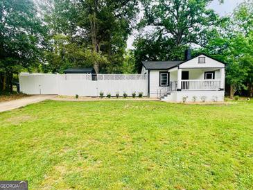 Charming one-story home boasts a lush lawn and white picket fence, blending comfort and classic style at 2502 Barge Sw Rd, Atlanta, GA 30331