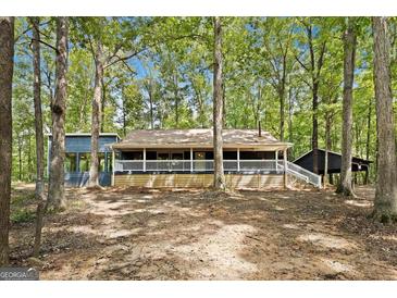 Charming ranch-style home surrounded by lush trees and a covered front porch, providing a serene curb appeal at 1597 Leguin Mill Rd, Locust Grove, GA 30248