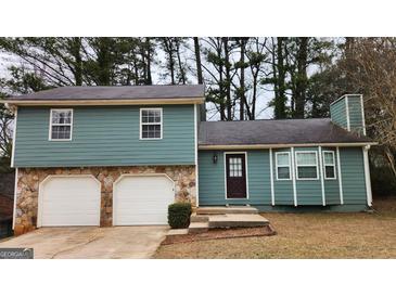 Split level home with a stone base, garage, and front door surrounded by green grass and trees at 5128 Running Fox Trl, Norcross, GA 30071