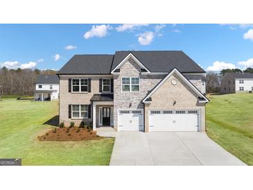 Beautiful two-story brick and stone home featuring a three-car garage and well-maintained landscaping at 679 Edgar, Hampton, GA 30228