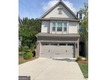 Charming home featuring a two-car garage, brick accents and manicured landscaping at 6398 Lanier Harbor Lndg, Buford, GA 30518