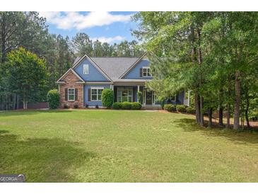 Charming blue two-story home featuring stone accents and a lush, well-manicured lawn surrounded by mature trees at 68 Timber Creek Estates Dr, Sharpsburg, GA 30277