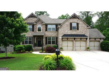 Charming brick home featuring a three-car garage and a beautifully landscaped front yard at 5760 Winding Lakes Dr, Cumming, GA 30028