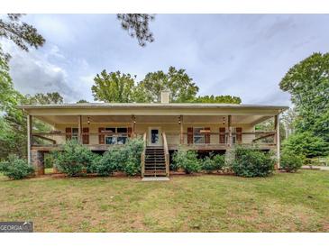 Charming ranch home featuring a wraparound porch, stone accents, and landscaped front yard at 4979 Snook Thompson Se Rd, Oxford, GA 30054