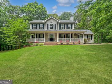 Charming two-story home with a welcoming porch, lush lawn, and surrounded by mature trees at 715 Frog Rd, Locust Grove, GA 30248