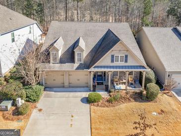Charming home with a three-car garage, dormers, front porch, and beautiful landscaping at 1141 Pebble Creek Ln, Locust Grove, GA 30248