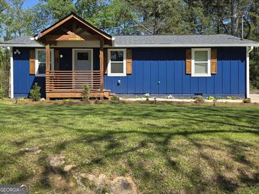 Charming home boasts a blue exterior with a cozy front porch, inviting curb appeal and mature trees at 95 Mccoy Dr, Carrollton, GA 30116