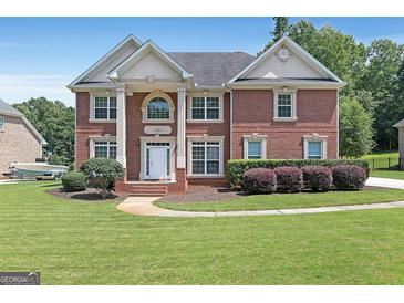 Elegant red brick home with a manicured lawn and stately white pillars at the front entry at 3183 Jackson Creek Dr, Stockbridge, GA 30281