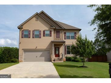 Charming two-story home with attached two-car garage and well-maintained front lawn and tasteful shutters at 8045 Coleson Xing, Locust Grove, GA 30248