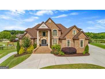 Stunning brick home featuring a manicured lawn, beautiful landscaping, and an arched stone entryway at 770 Tralee Dr, Fayetteville, GA 30215