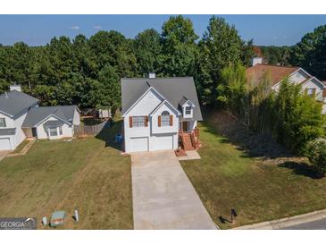 Charming two-story home with a well-manicured lawn and a two-car garage and mature trees in the background at 10074 Tara Glynn Dr, Hampton, GA 30228