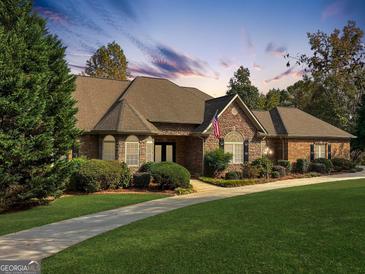 Charming stone and brick home with lush lawn and manicured landscaping under a beautiful twilight sky at 232 Darwish Dr, Mcdonough, GA 30252