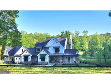 Inviting home exterior with black roof, stone accents, white siding, and mature landscaping at 155 Green Meadow Ln, Fayetteville, GA 30215