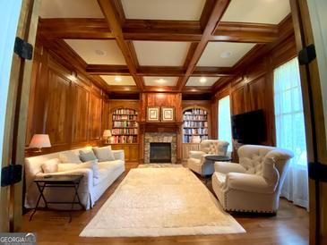 Beautiful living room with wood paneled walls, coffered ceiling, fireplace, and built-in bookshelves at 1345 Cashiers Way, Roswell, GA 30075